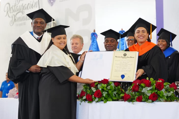 El rector de la UASD, maestro Editrudis Beltrán Crisóstomo, entrega su diploma a la graduada del nivel de grado, en la carrera Doctor en Medicina, Katherine Nicole Moya Ortiz, quien alcanzó el índice más alto 94.6.