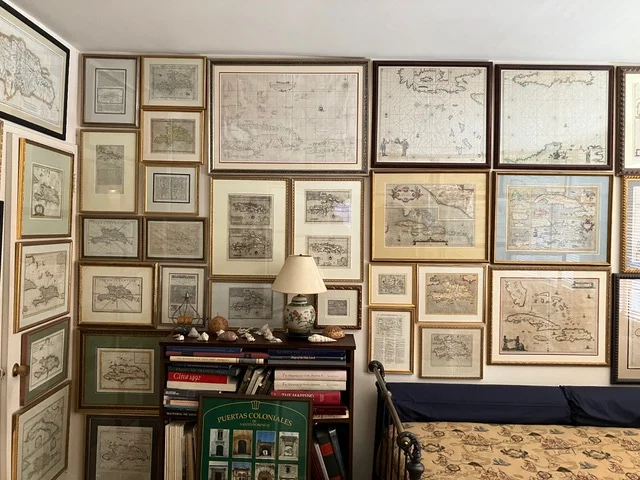  Pared de la colección privada de Joseph González y Ralph Magnus, cubierta con mapas antiguos de La Española y el Caribe enmarcados y dispuestos en un dinámico conjunto visual.