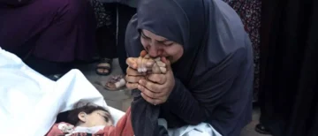  La madre de dos mellizos de 8 años fallecidos en un bombardeo israelí besa sus manos en el hospital Al Aqsa de Gaza. Foto AFP
