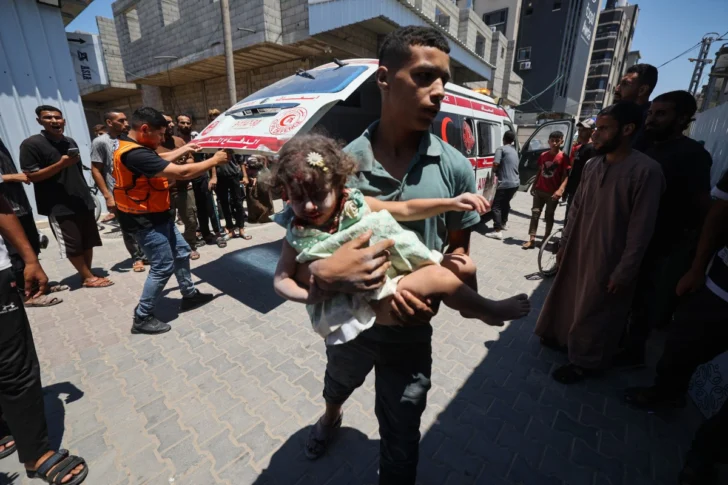  Un joven palestino lleva a una niña herida en un ataque israelí en el centro de la Franja de Gaza, el 19 de julio de 2025. (Foto de Eyad BABA / AFP)