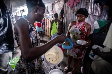  PUERTO PRÍNCIPE (HAITÍ), 19/08/2025.- Fotografía del 14 de agosto de 2025 de una mujer recibiendo comida para su familia en el campamento de refugiados OPC, en Puerto Príncipe (Haití). 