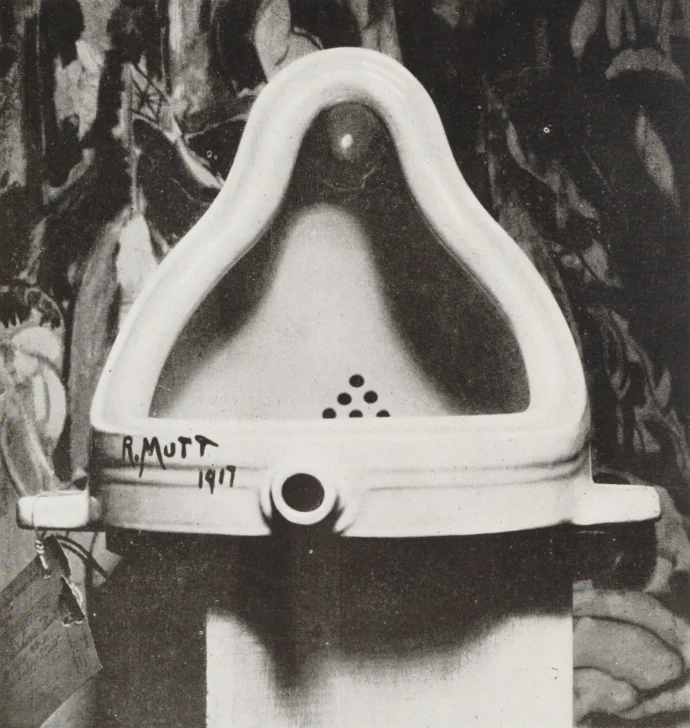  La obra original fotografiada por Alfred Stieglitz en el 291 después de la exposición de 1917 de la Sociedad de Artistas Independientes. Stieglitz utilizó un telón de fondo de The Warriors de c para fotografiar el urinario. La etiqueta de entrada de la exposición se puede ver claramente. Autor: Marcel Duchamp. Creación 1917.