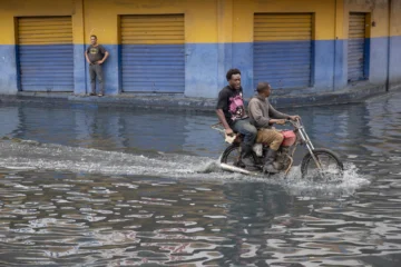  AME863. SANTO DOMINGO (REPÚBLICA DOMINICANA), 23/10/2025.- Personas recorren una calle inundada este jueves, en Santo Domingo (República Dominicana). Más de 647.000 usuarios están sin agua potable en República Dominicana después de que las lluvias provocadas por la tormenta tropical Melissa afectaran decenas de acueductos. EFE/ Orlando Barría