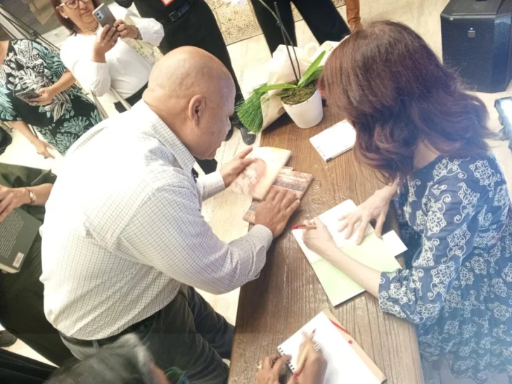  Enegildo Peña, haciéndole entrega de sus dos libros publicados más recientes, Voces de mi voz y Contextos desde la lengua.